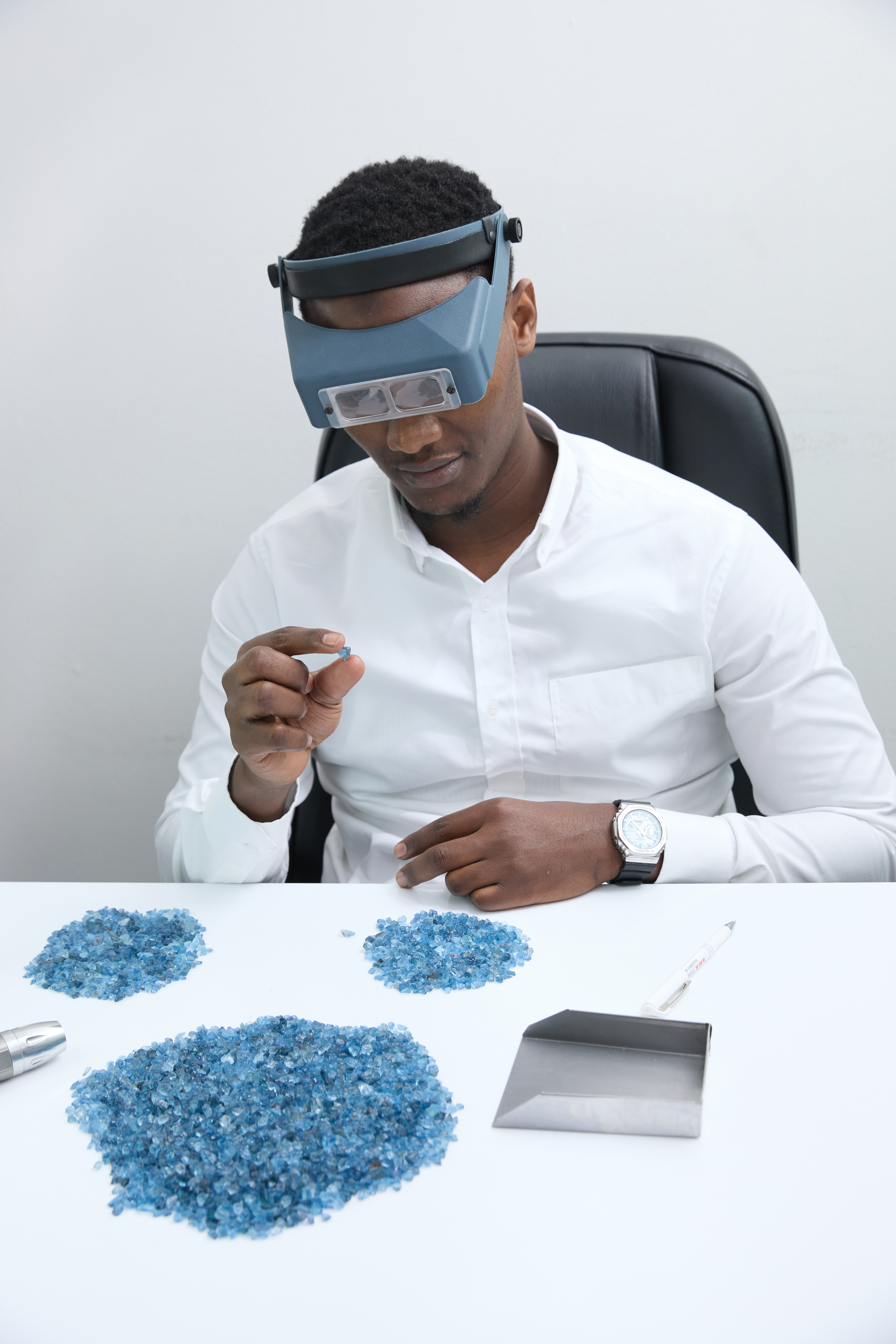 Gemologist inspecting rough aquamarine under a loupe